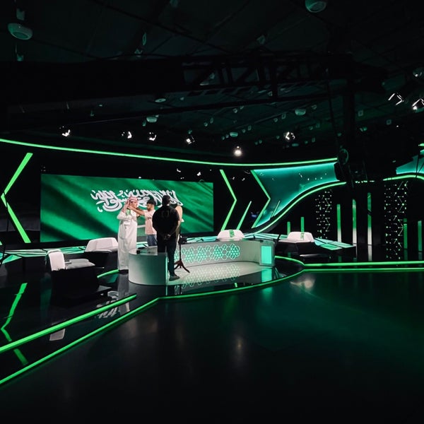 Green LED studio floor mid-shoot, Saudi flag on the video wall